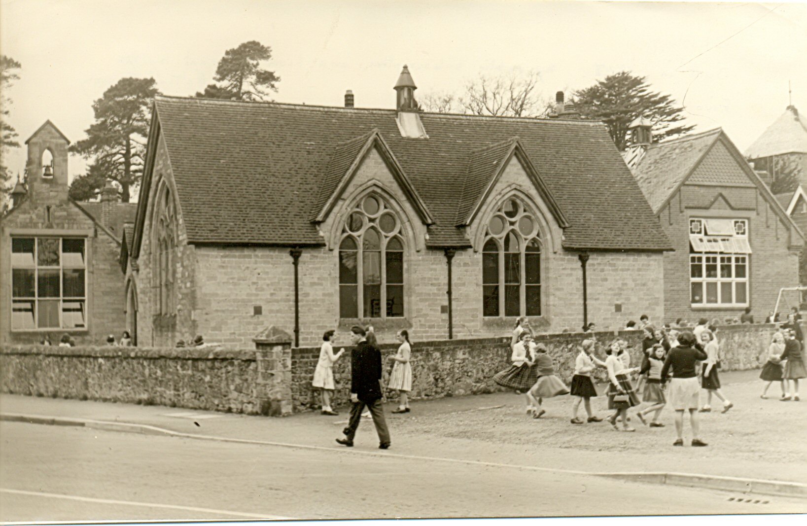 Black and white photograph of the National School in Cranleigh after the new classrooms were added in 1871. Children are playing outside