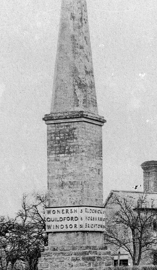 Black and white photograph of a tall Egyptian-looking monument with direction plates saying 31 miles to both Windsor and Brighton
