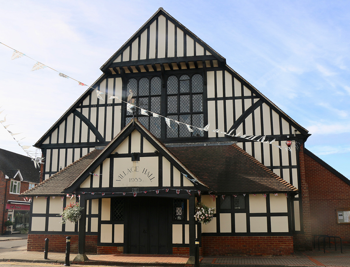 A large building with black timbers on a white background decorated with celebratory bunting